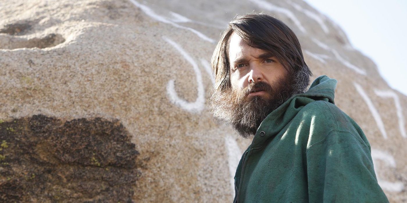Phil standing by a mountain with a green sweater and beard in The Last Man on Earth.