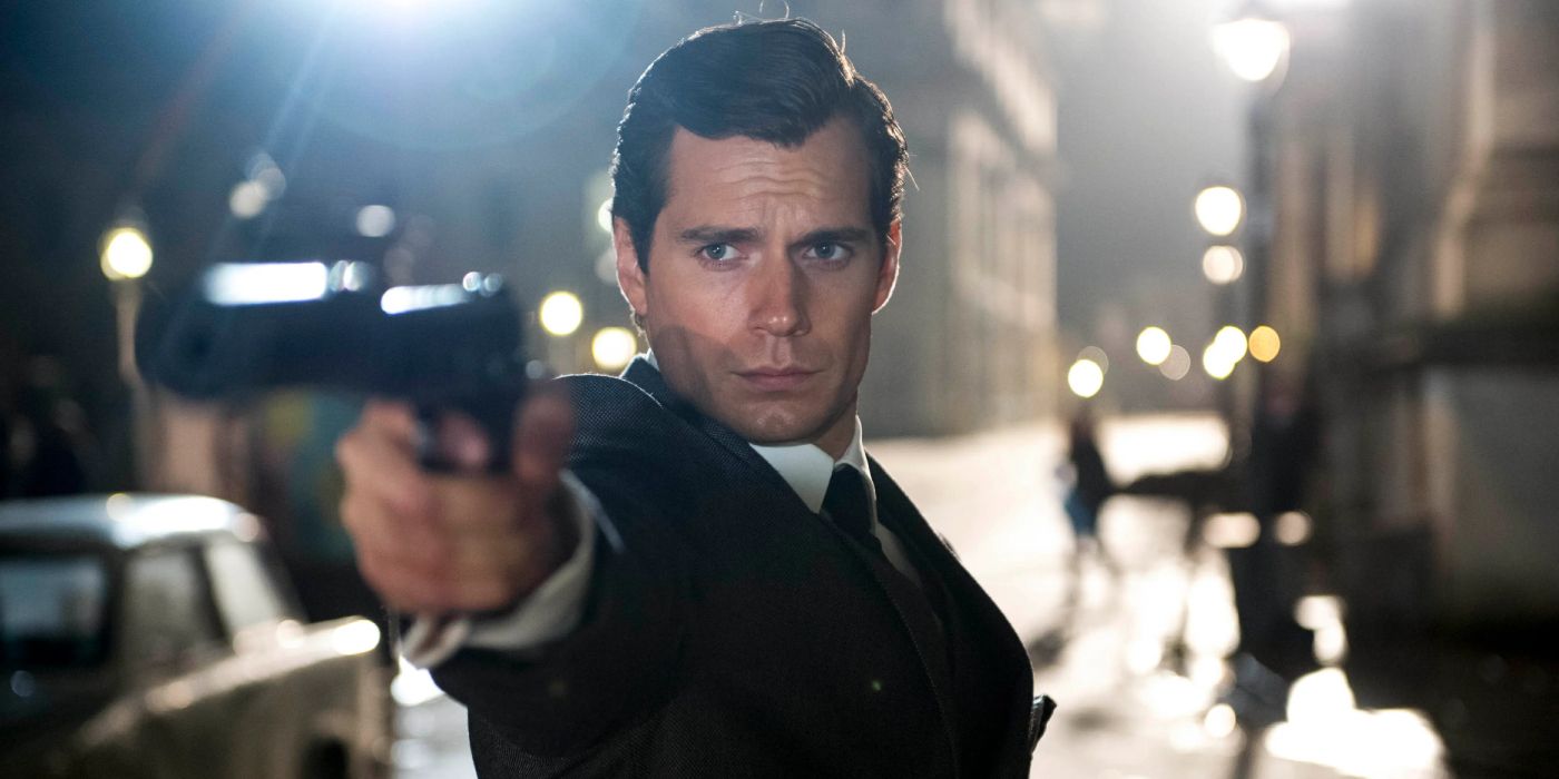 Napoleon Solo stands in a European street at night, wearing a suit, & aims his pistol