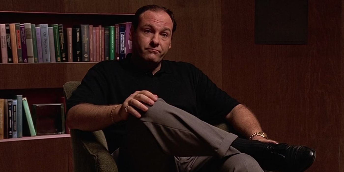 Tony Soprano (James Gandolfini) sits in his therapist, Dr. Melfi's (Lorraine Bracco), office with his leg crossed over his knee.