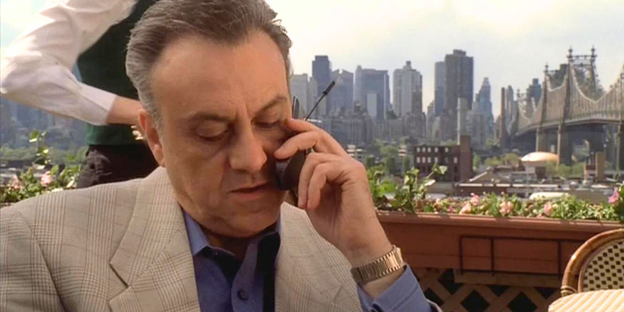 Vincent Curatola as Johnny Sack on the phone while sitting at a table in The Sopranos