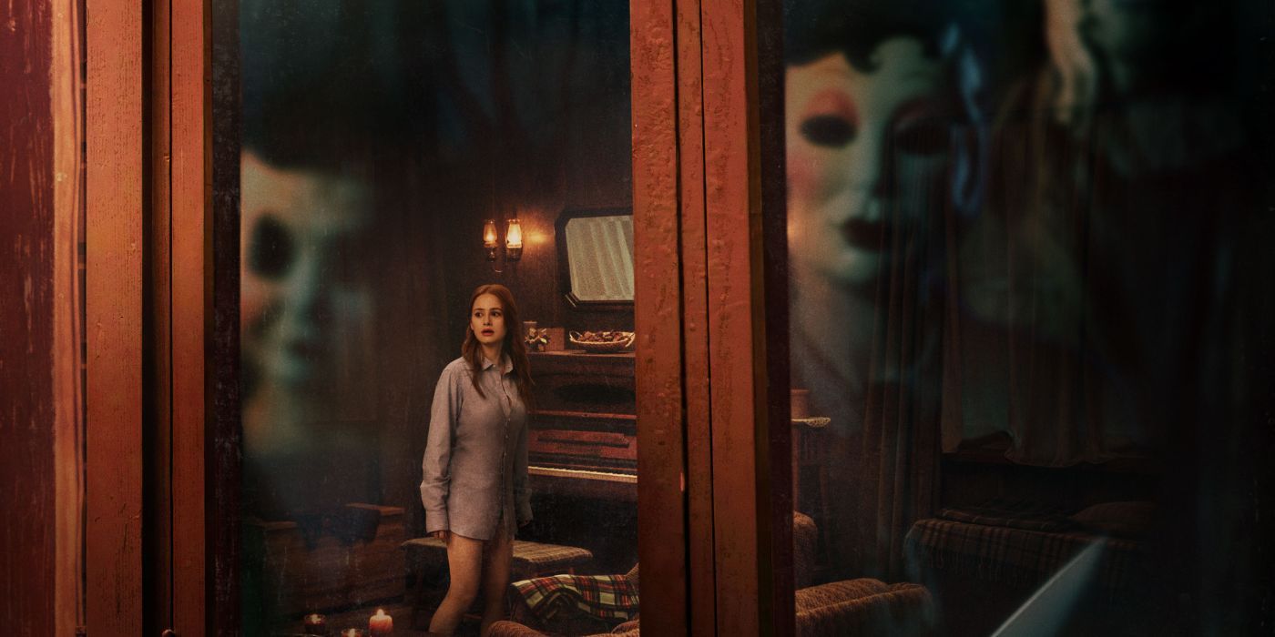 Madelaine Petsch looking scared while the Strangers' masks reflect on the window.