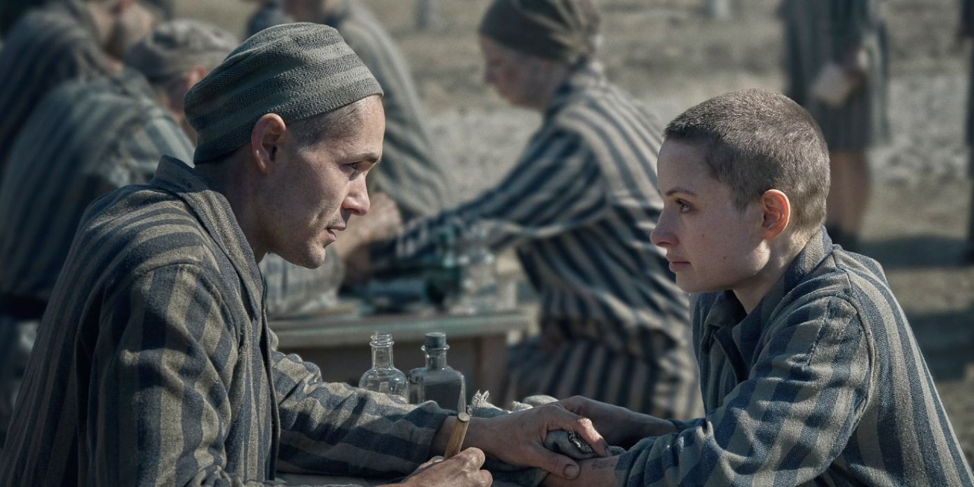 Jonah Hauer-King i Anna Próchniak s'agafen les mans amb uniformes de ratlles a The Tattooist of Auschwitz
