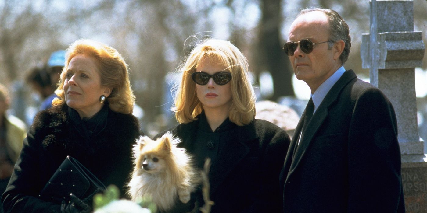 Earl (Kurtwood Smith), Carol (Holland Taylor) y Suzanne Stone (Nicole Kidman) están en un cementerio vestidos de negro, Suzanne sostiene un perro en To Die For