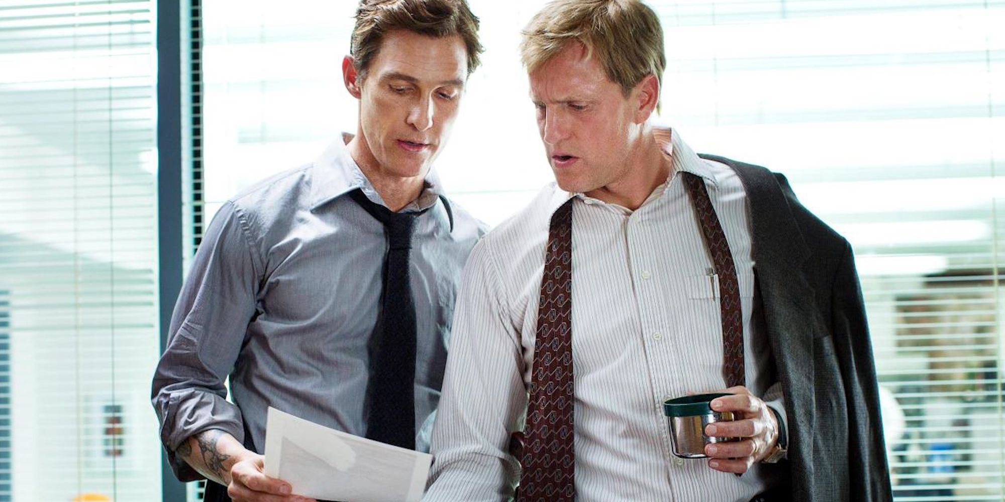 Matthew McConaughey and Woody Harrelson looking at a sheet of paper together on True Detective.