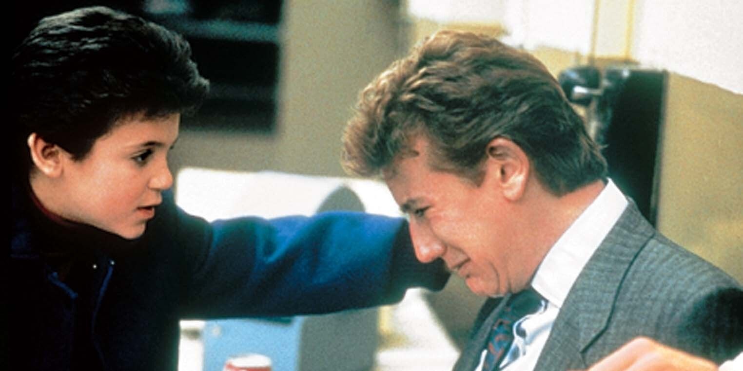 A still from Vice Versa featuring Fred Savage as Charlie Seymour consoling Judge Reinhold as Marshall Seymour