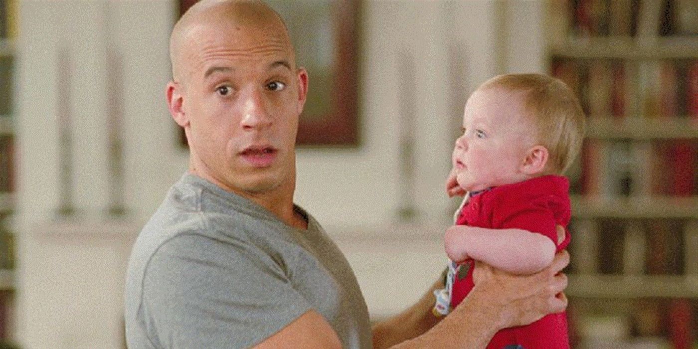 Vin Diesel as Shane looking surprised whie holding a baby in The Pacifier