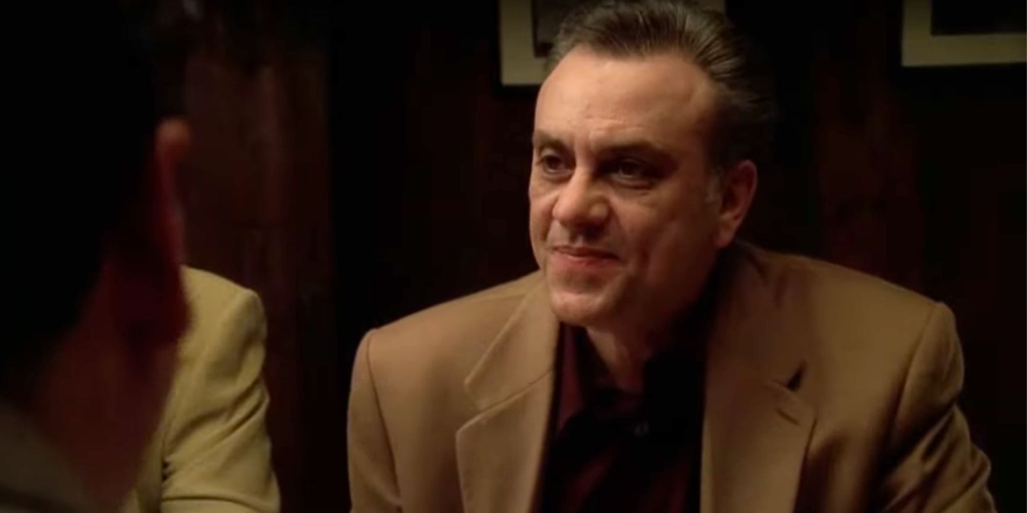Vincent Curatola as Johnny Sack sitting at a dinner table with several others in The Sopranos
