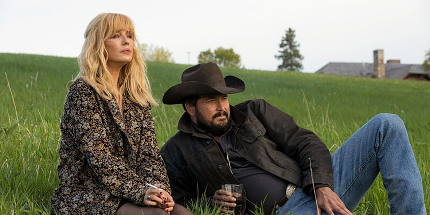Kelly Reilly and Cole Hauser lounging in a grassy meadow in Yellowstone Season 5