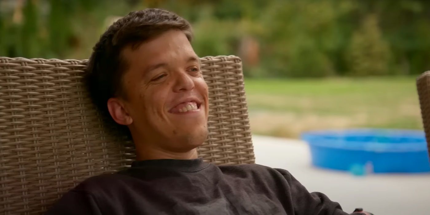 Zach Roloff, sitting on a wooden chari while smiling, in TLC's Little People, Big World