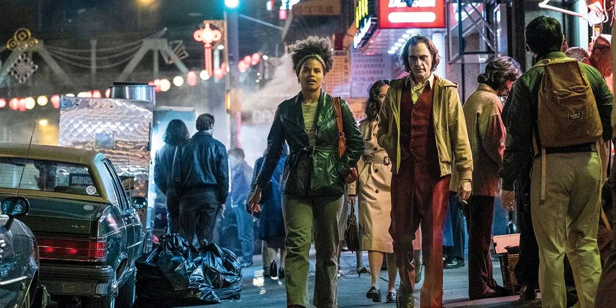 Zazie Beetz and Joaquin Phoenix walking side by side on the street in Joker.