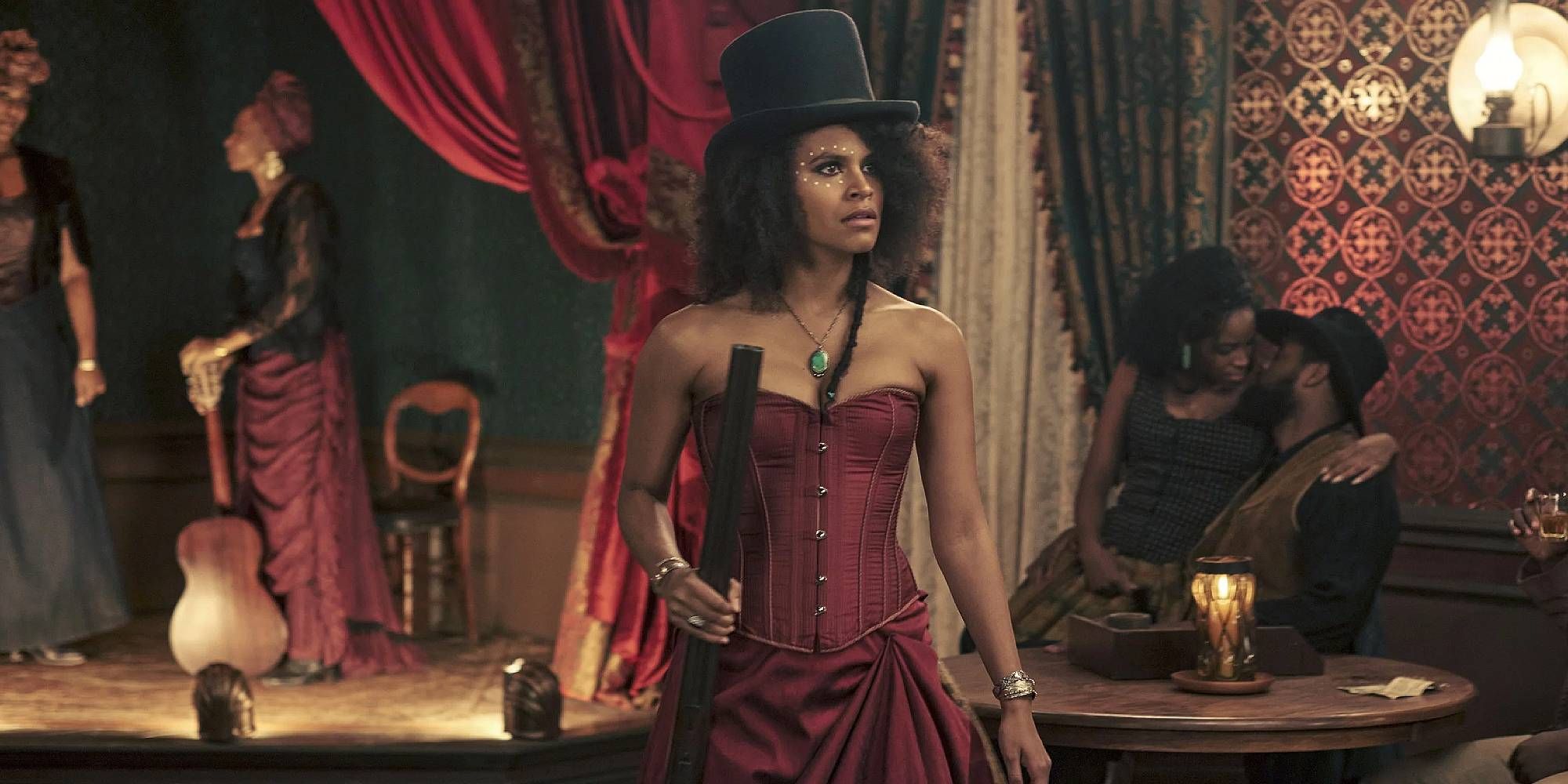 Zazie Beetz in The Harder They Fall holding a gun and wearing a red dress.