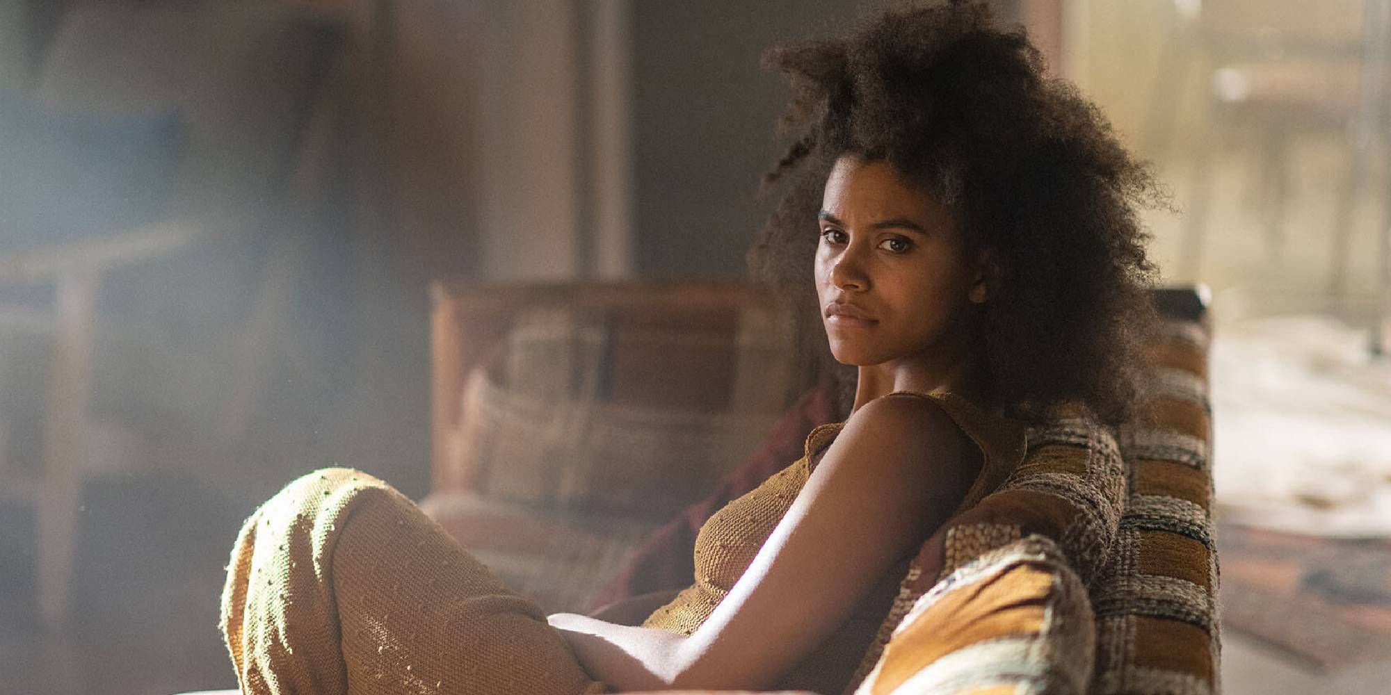Zazie Beetz sitting on a couch while looking to her left in Nine Days.
