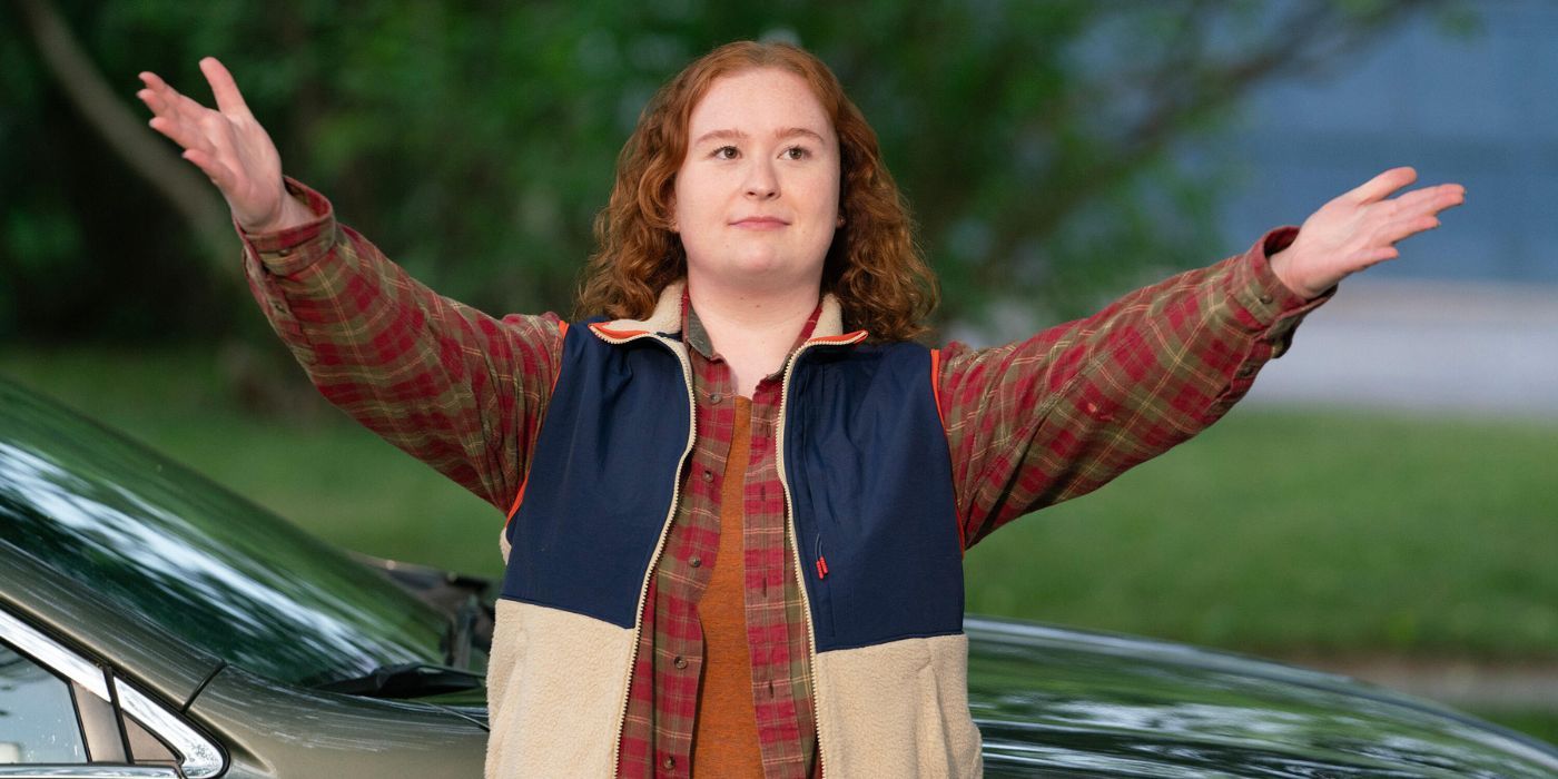 Julia Lester wearing a vest over a plaid shirt, spreading out her arms.