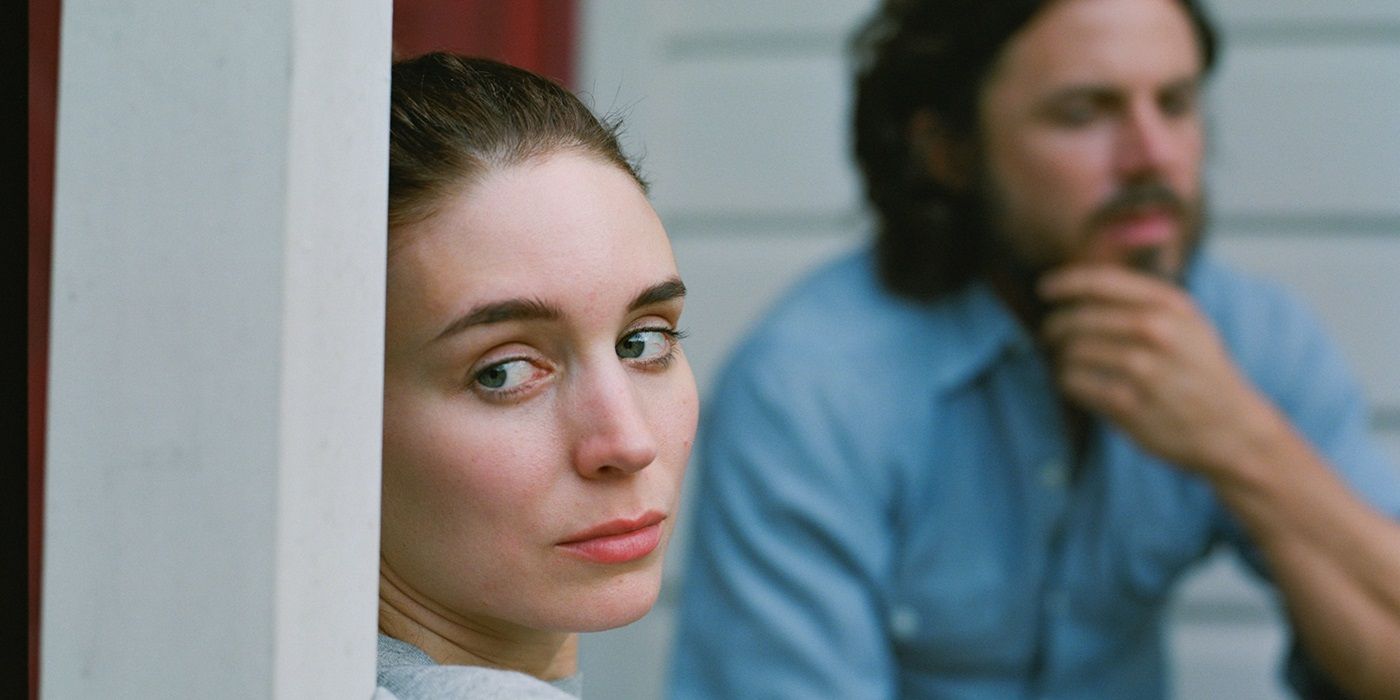 Casey Affleck as C sitting behind Rooney Mara as M in A Ghost Story