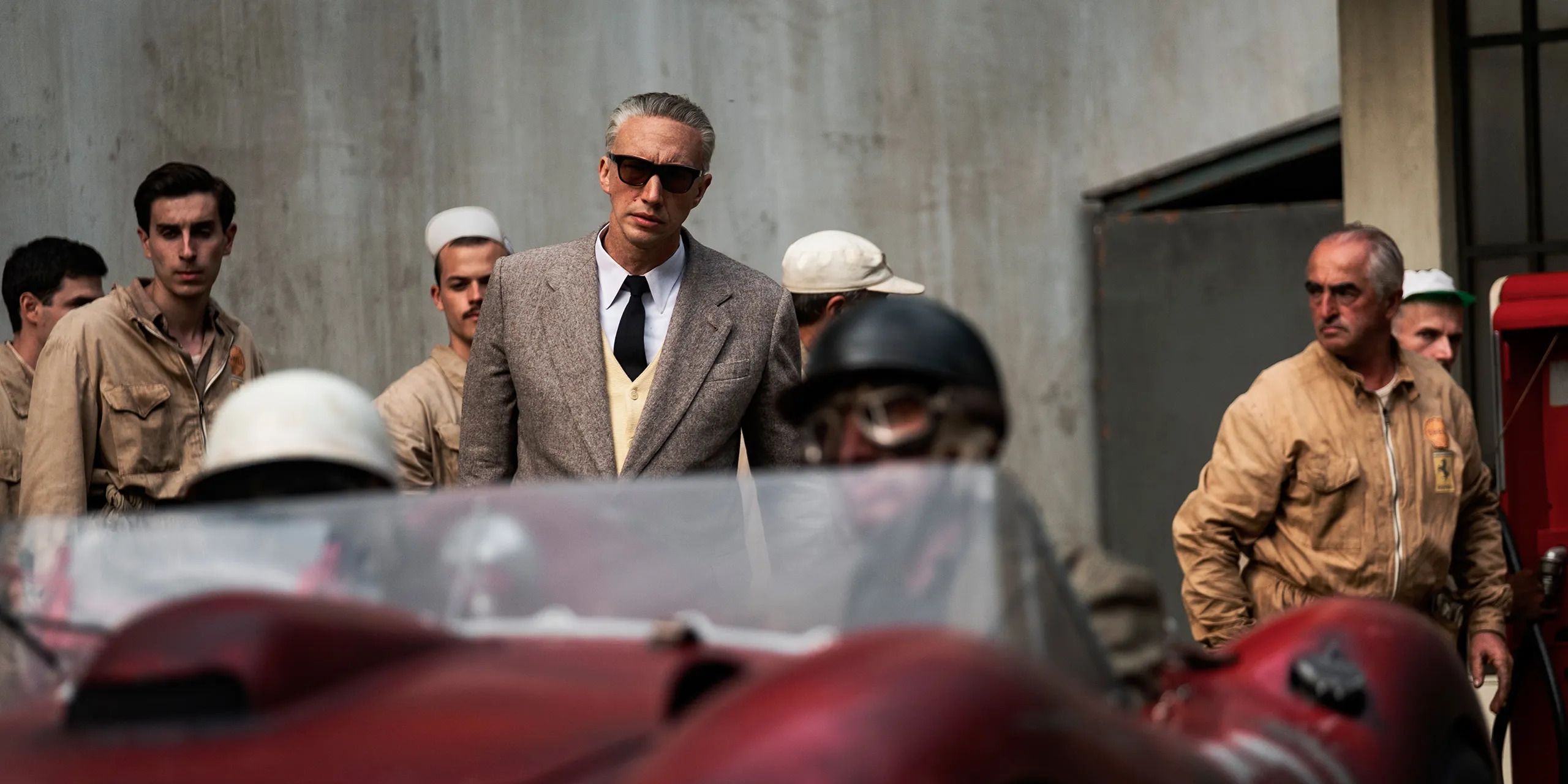 Adam Driver and a team of mechanics look over a car in Michael Mann's 'Ferrari'