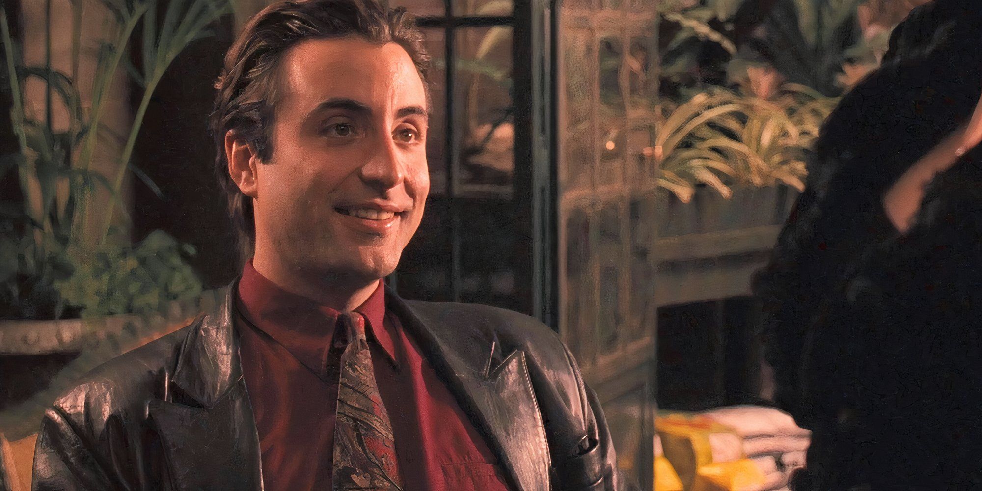 Vincent Corleone sitting at a table and smiling in The Godfather: Part III (1990)