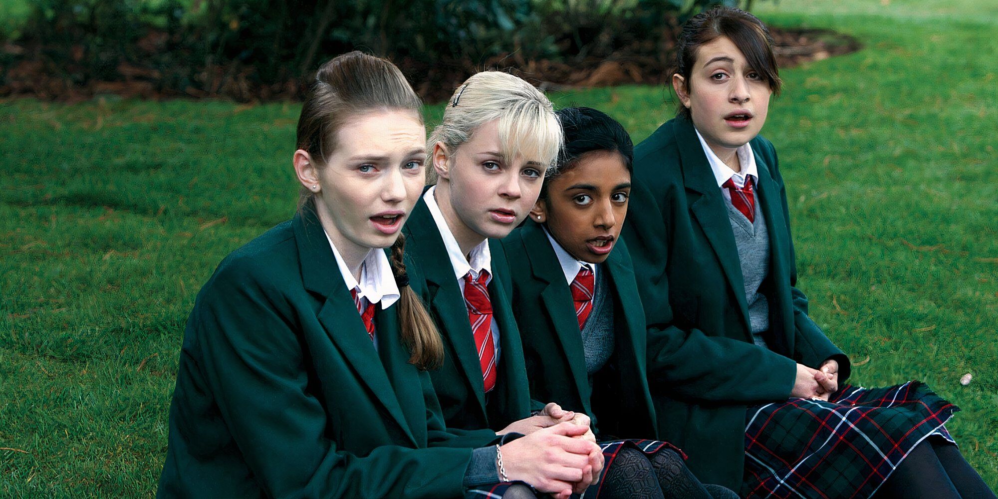 A clique of young school girls wearing their uniforms and sitting on the grass in 'Angus, Thongs and Perfect Snogging' (2008)