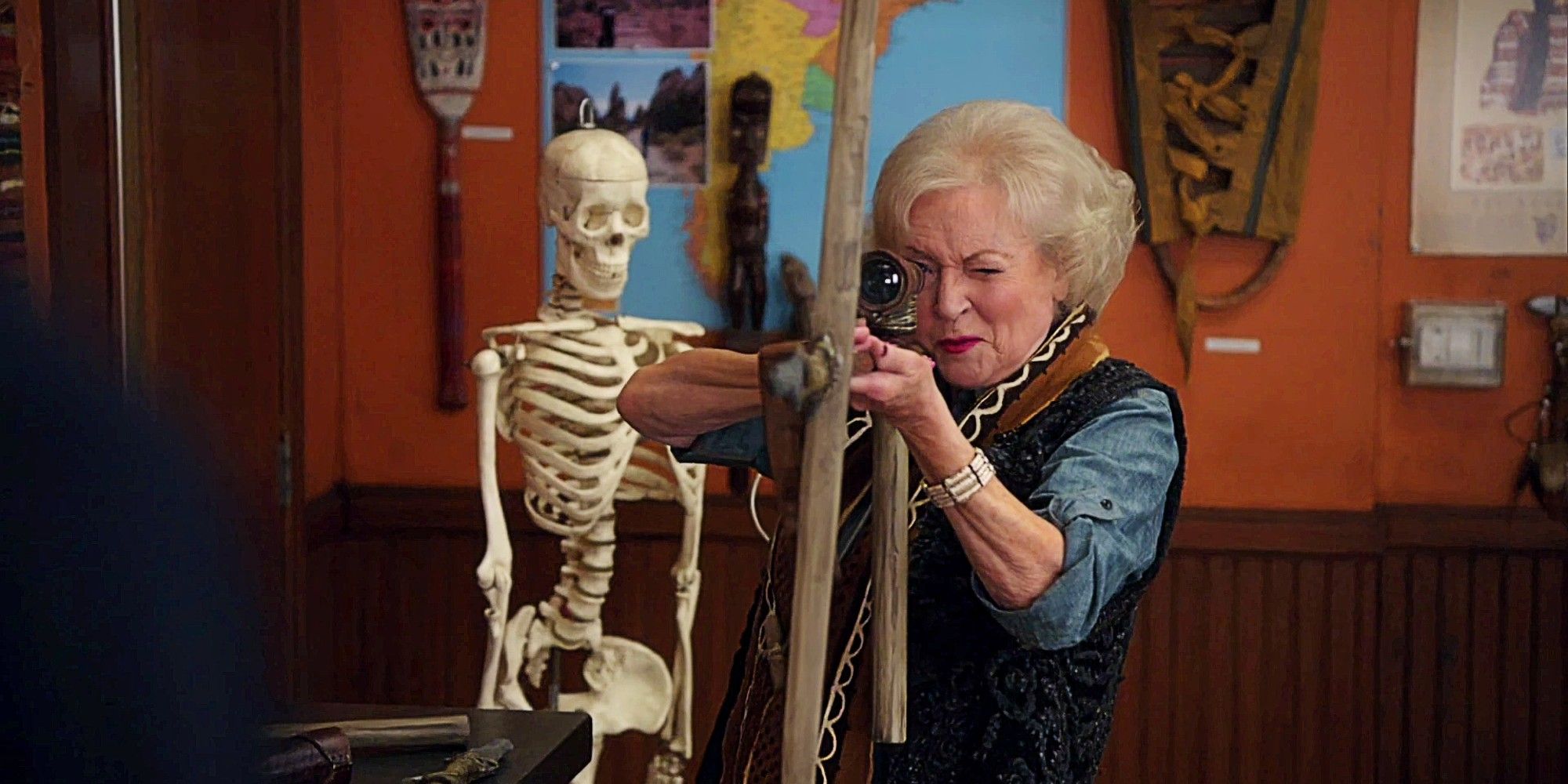 Betty White as Professor June Bauer in Community, aiming a large weapon