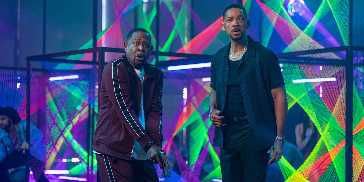Martin Lawrence and Will Smith look confused while standing in a club with red and green strobe lights.