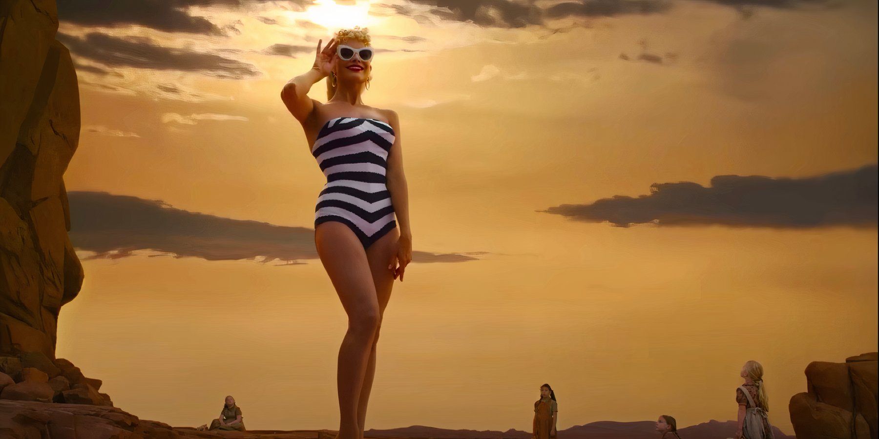 A comically enlarged Barbie, played by actor Margot Robbie, stands amid a small group of young girls in the desert in an homage to 2001: A Space Odyssey in the opening moments of 2023’s Barbie.