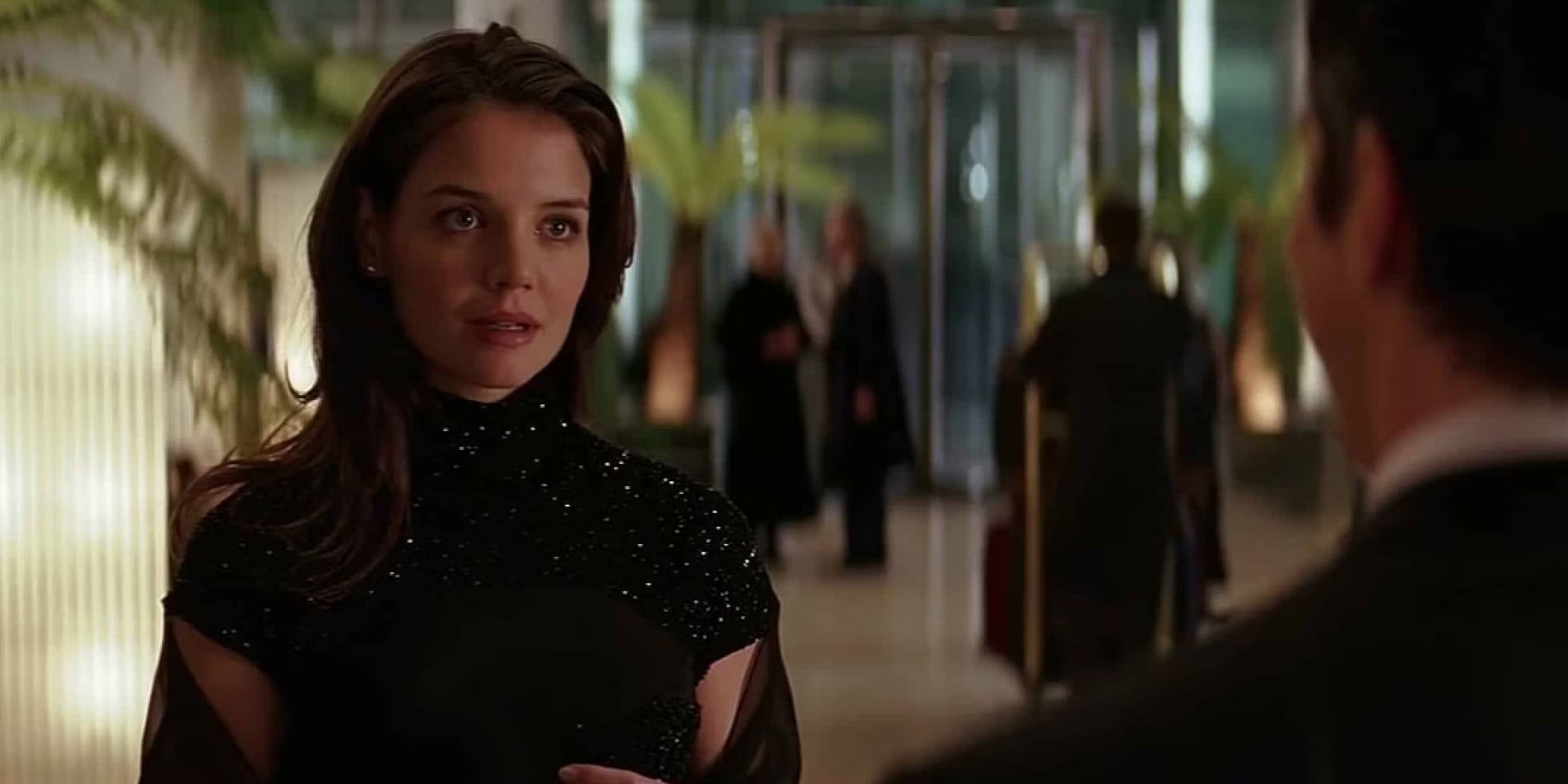 Rachel Dawes (Katie Holmes) stands in a sparkly dress at a fancy event as she confronts Bruce Wayne about his actions in 'Batman Begins' (2005).