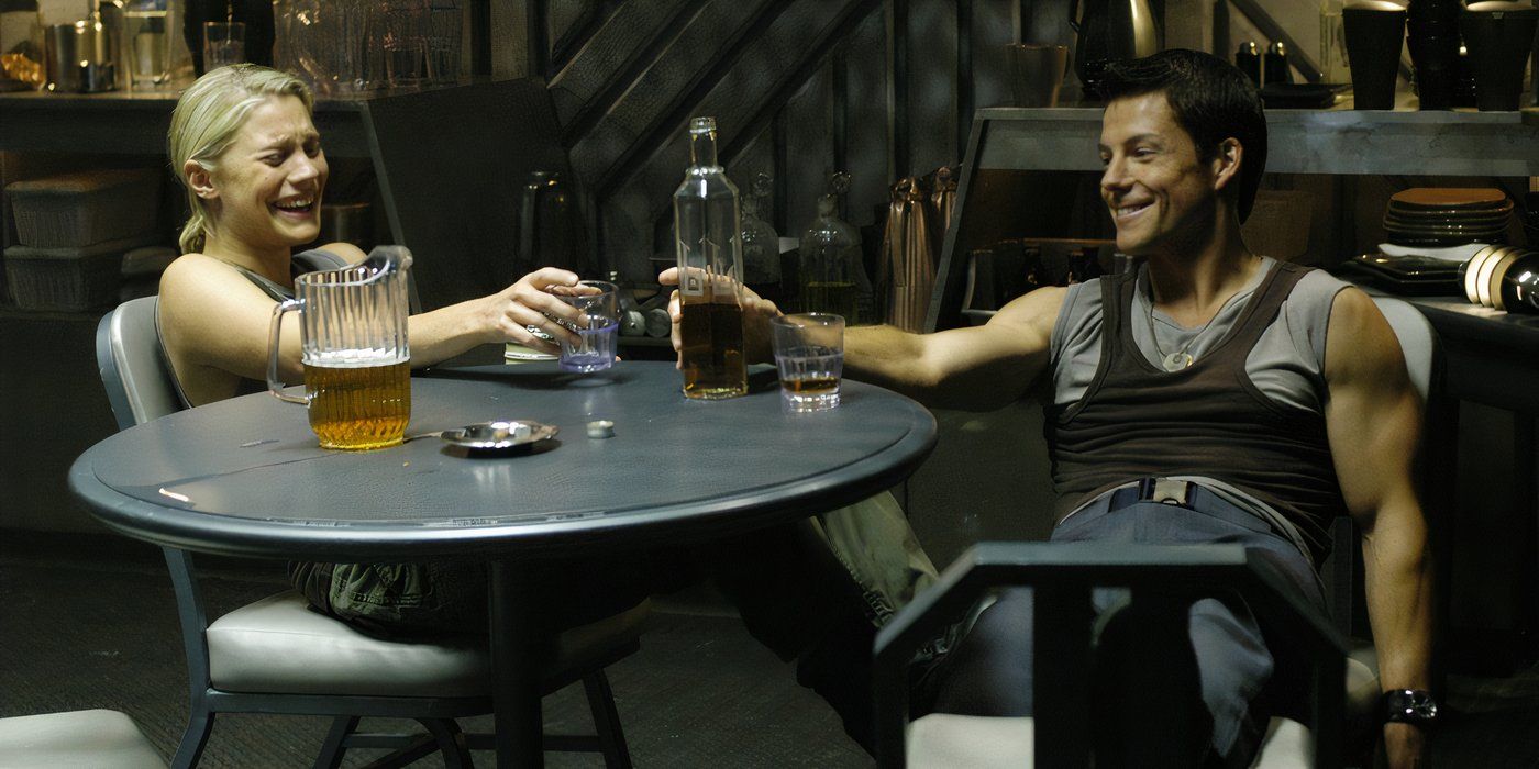 Kara Thrace (Katee Sackhoff) and Lee Adama (Jamie Bamber) sitting at a table together and laughing as they drink in Battlestar Galactica