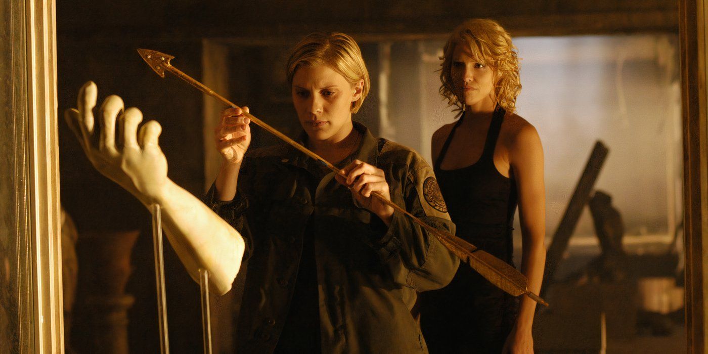 Kara Thrace (Katee Sackhoff) holding a golden arrow while Six (Tricia Helfer) looms menacingly behind her in Battlestar Galactica