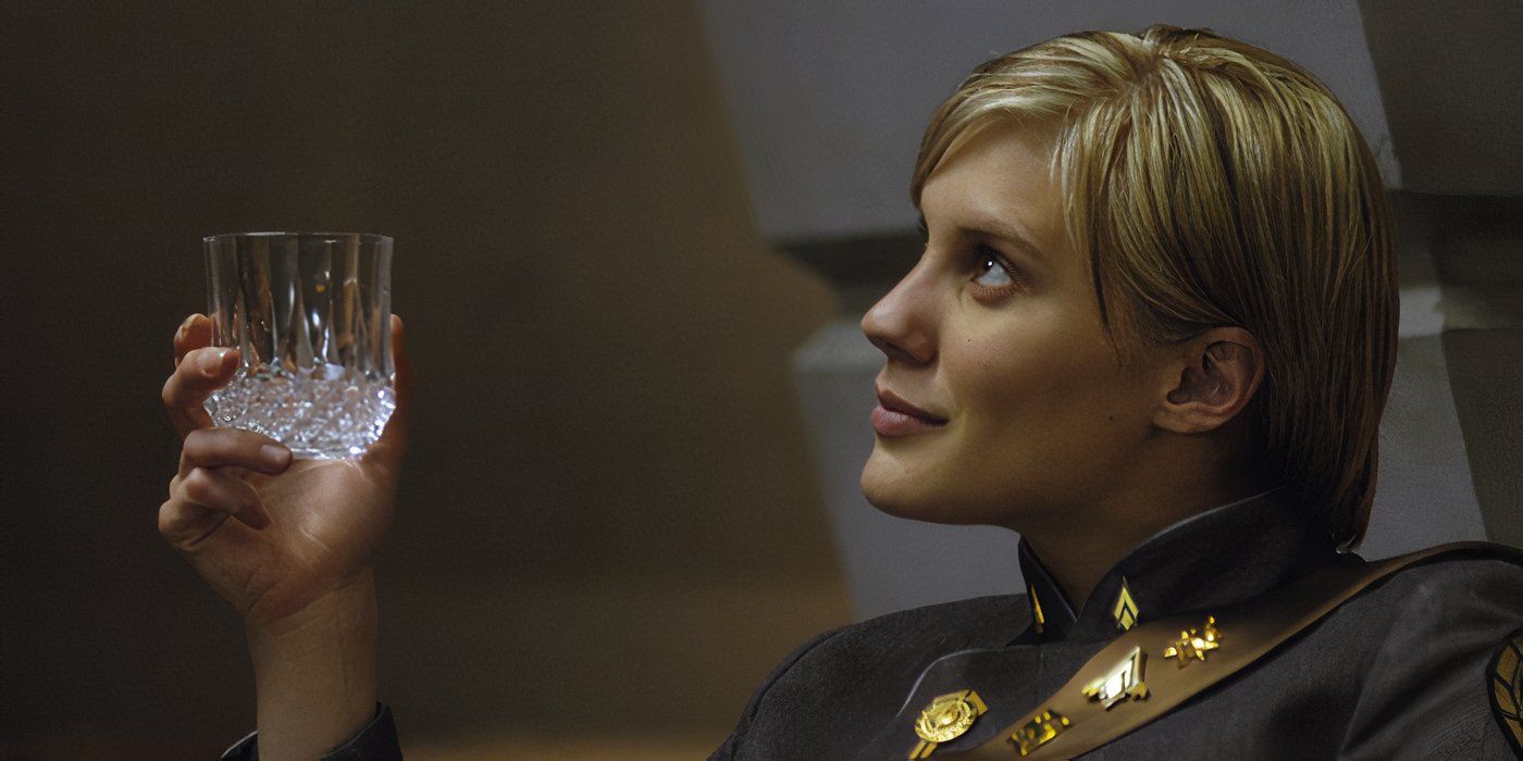 Kara Thrace (Katee Sackhoff) looking offscreen to the left and smiling slightly while holding a drink glass in Battlestar Galactica