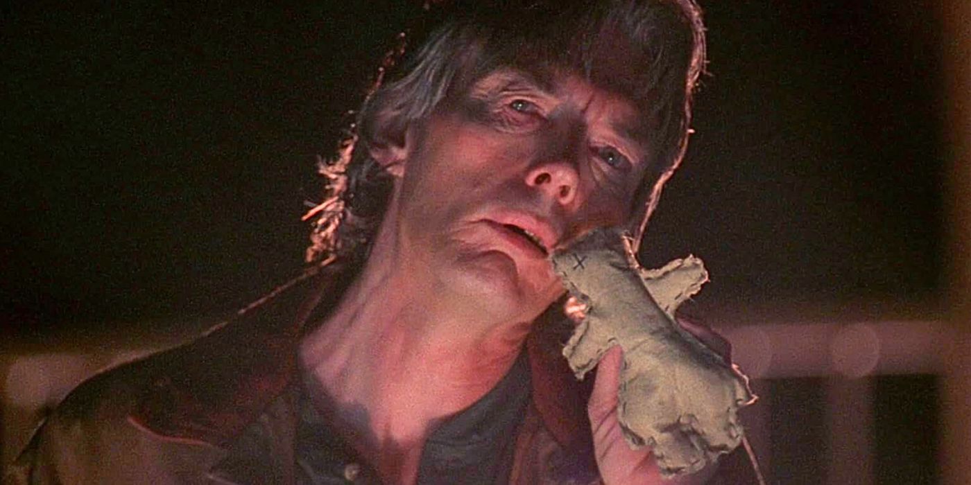 Billy-Drago as Peattie holds a voodoo doll next to his cheek in episode Theef from The X-Files