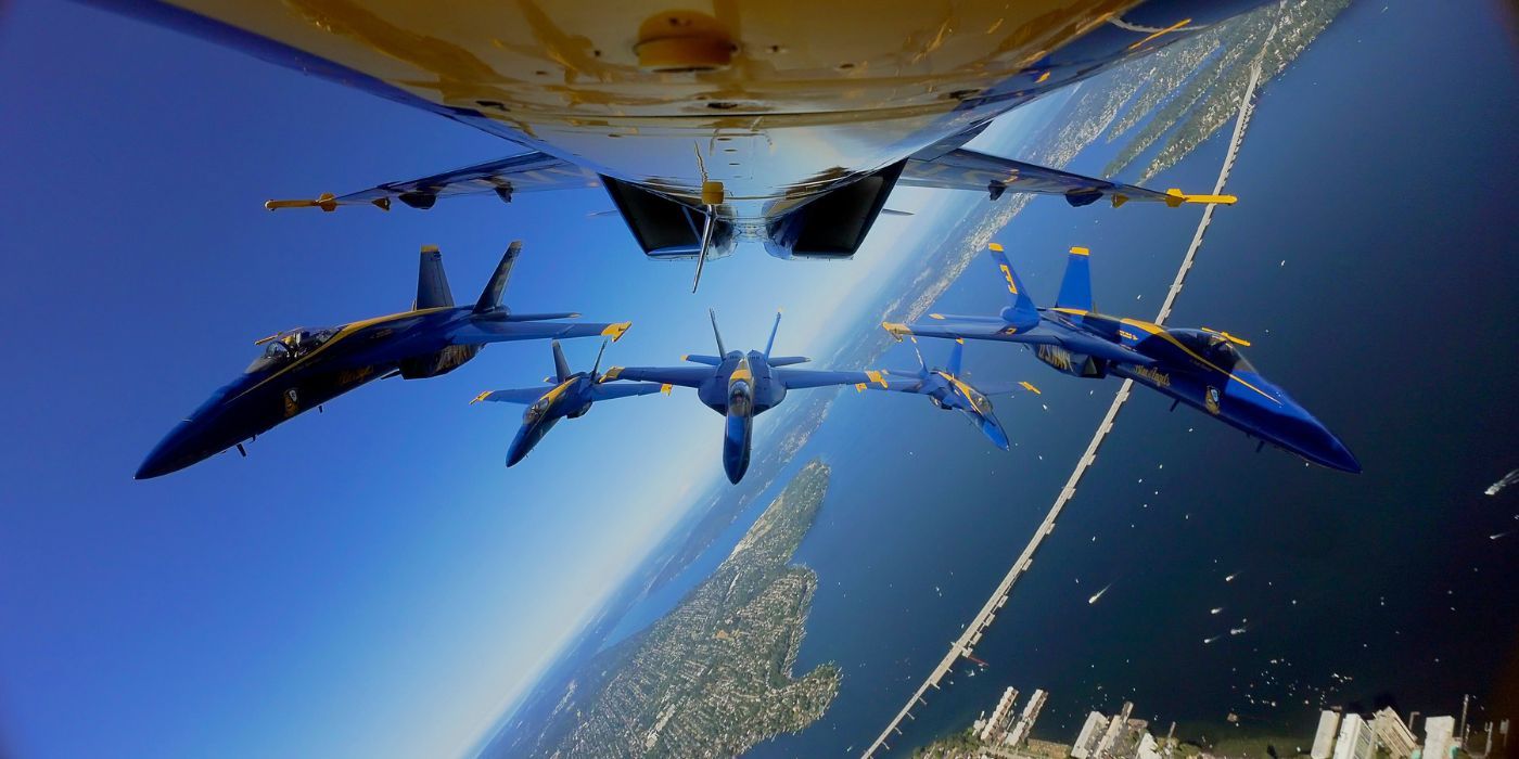Three Blue Angel jets flying in formation behind another jet.