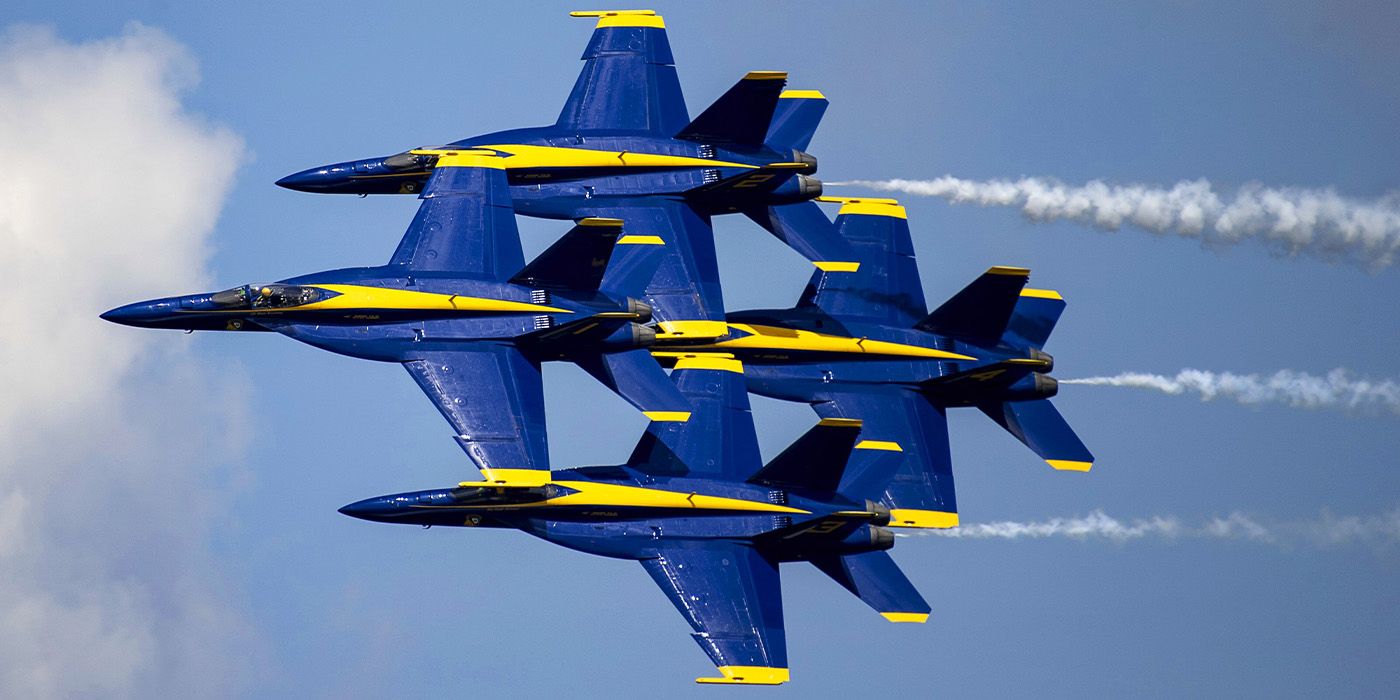 The Blue Angels jets perform a formation in a blue sky with jet streams trailing behind