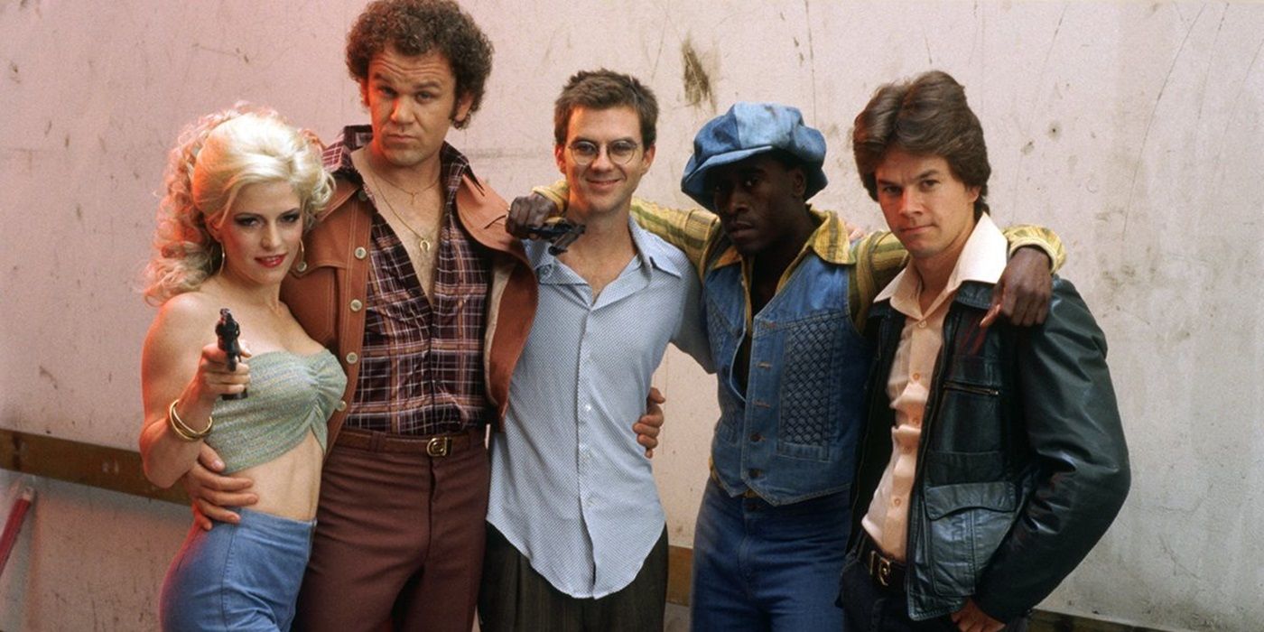 Paul Thomas Anderson standing with the cast of Boogie Nights such as Melora Walters, John C. Reilly, Don Cheadle, and Mark Wahlberg.