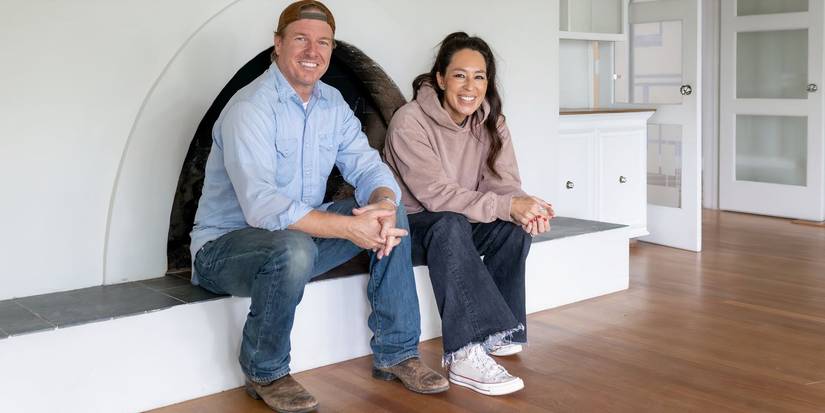 Chip and Joanna Gaines sitting inside by a fireplace