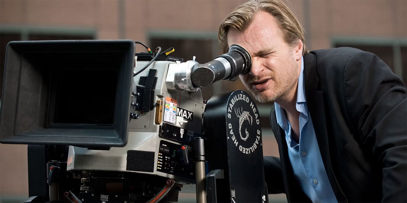 Christopher Nolan leans down to look through an IMAX camera