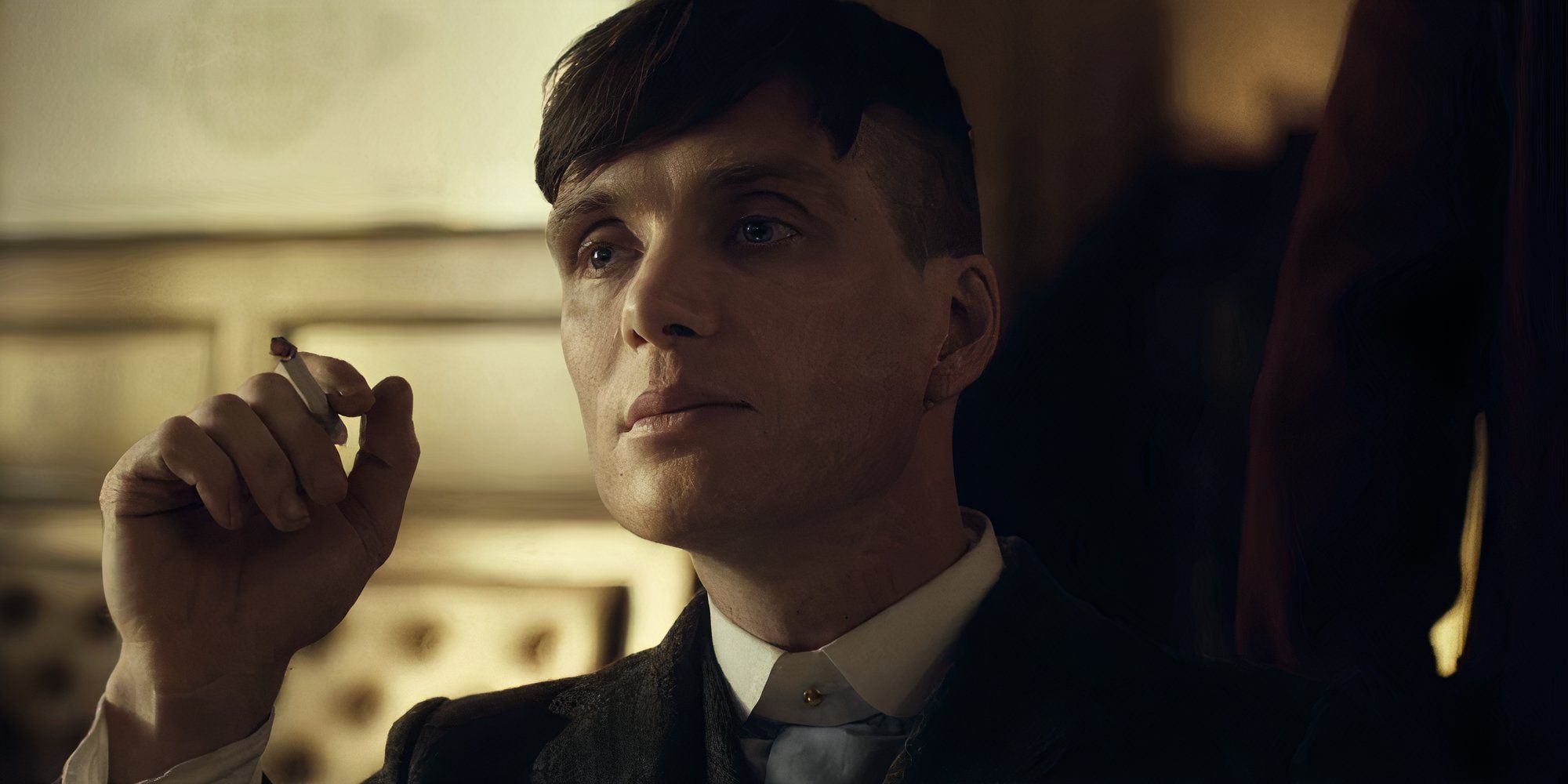 Cillian Murphy as Tommy Shelby holding a cigarette in Peaky Blinders.