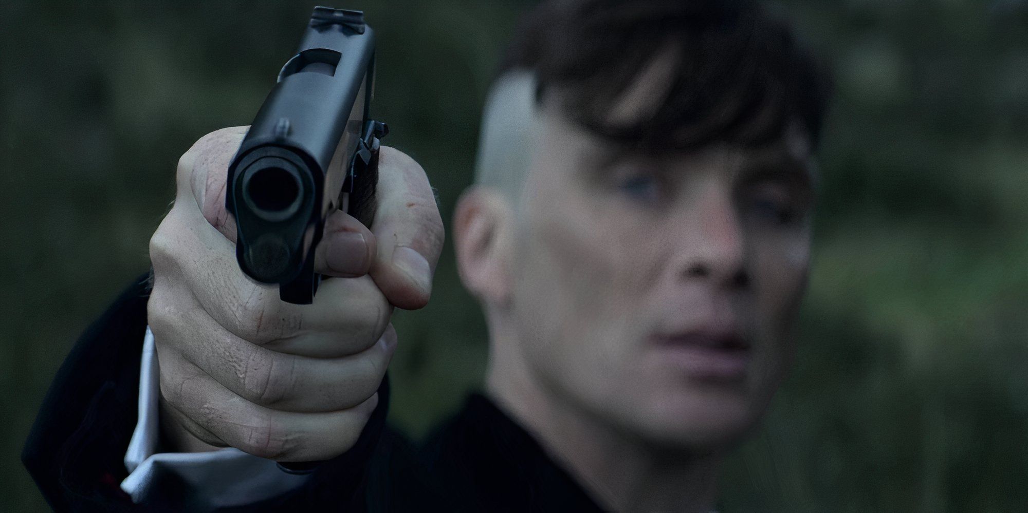 Cillian Murphy as Tommy Shelby pointing a gun at the camera in Peaky Blinders.