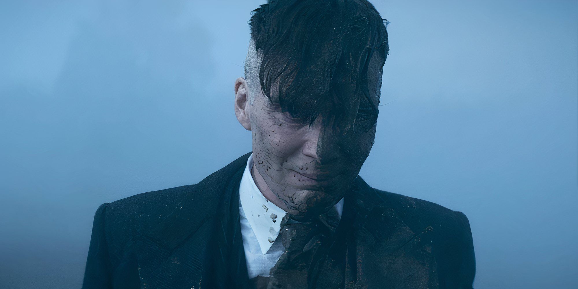 Cillian Murphy as Tommy Shelby with half his face covered in mud in Peaky Blinders.