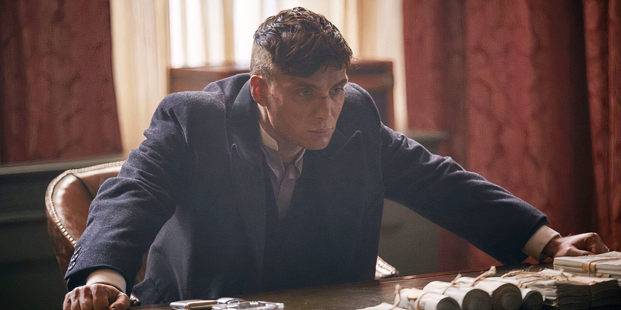 Cillian Murphy in Peaky Blinders leaning over his desk.