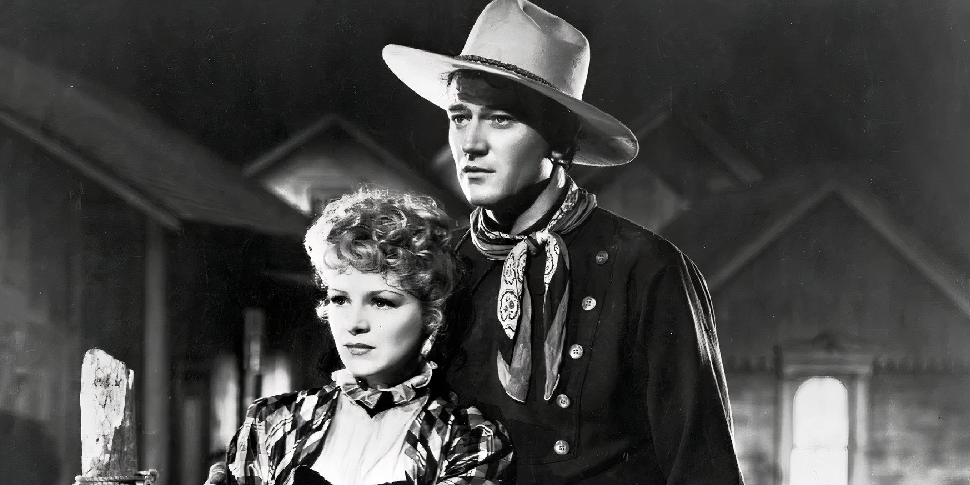 Claire Trevor as Dallas and John Wayne as Ringo the Kid standing next to each other in Stagecoach