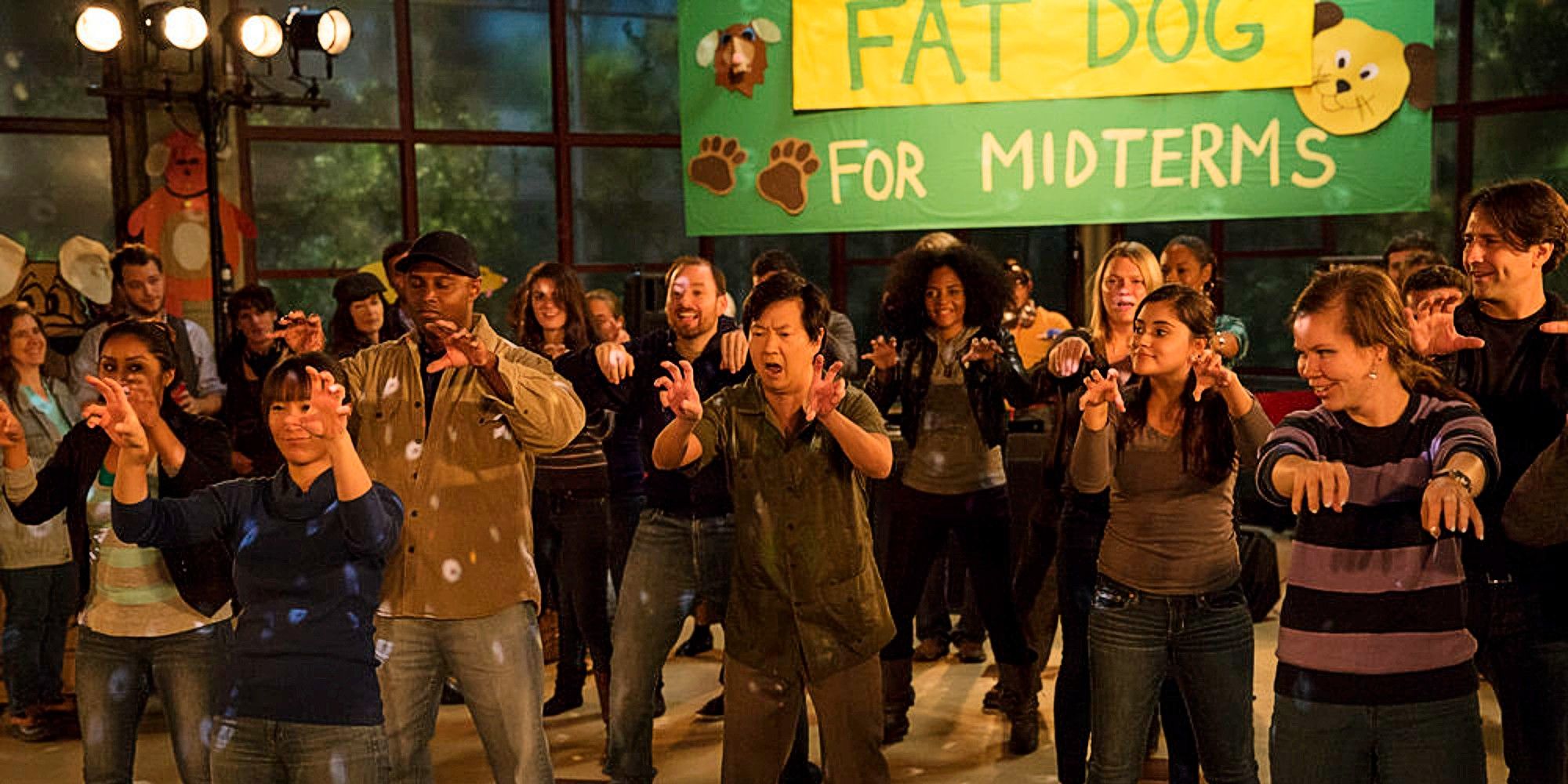 Chang leading the "Fat Dog" dance in Community in front of a sign that reads "FAT DOG FOR MIDTERMS"