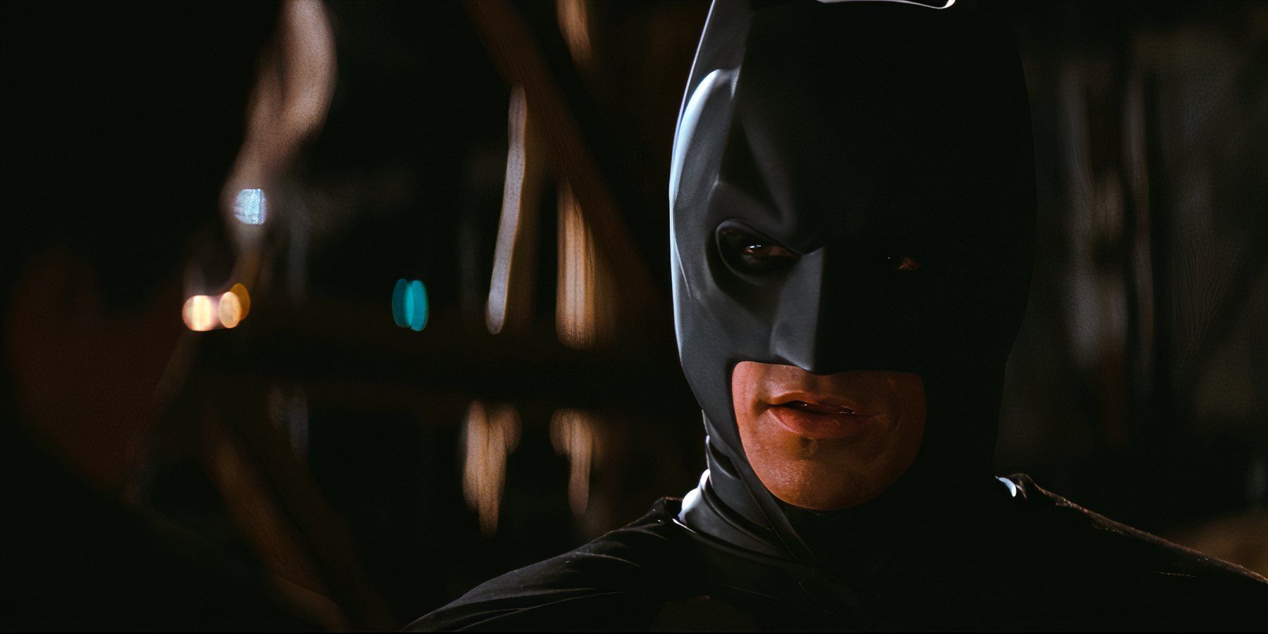 Batman addresses Jim Gordon in an empty warehouse, cloaked in shadow in The Dark Knight.