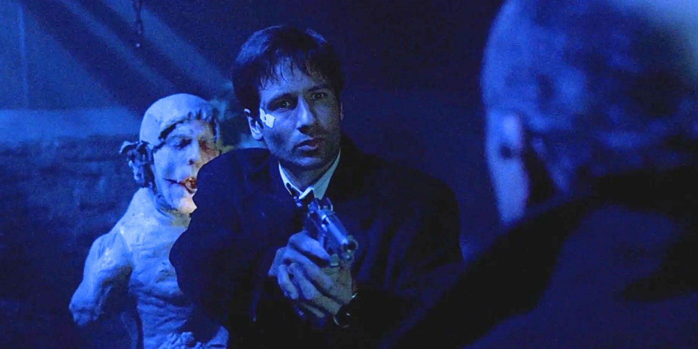 David Duchovny is surrounded by gargoyles and points his weapon at killer off-screen in episode Grotesque in The X-Files