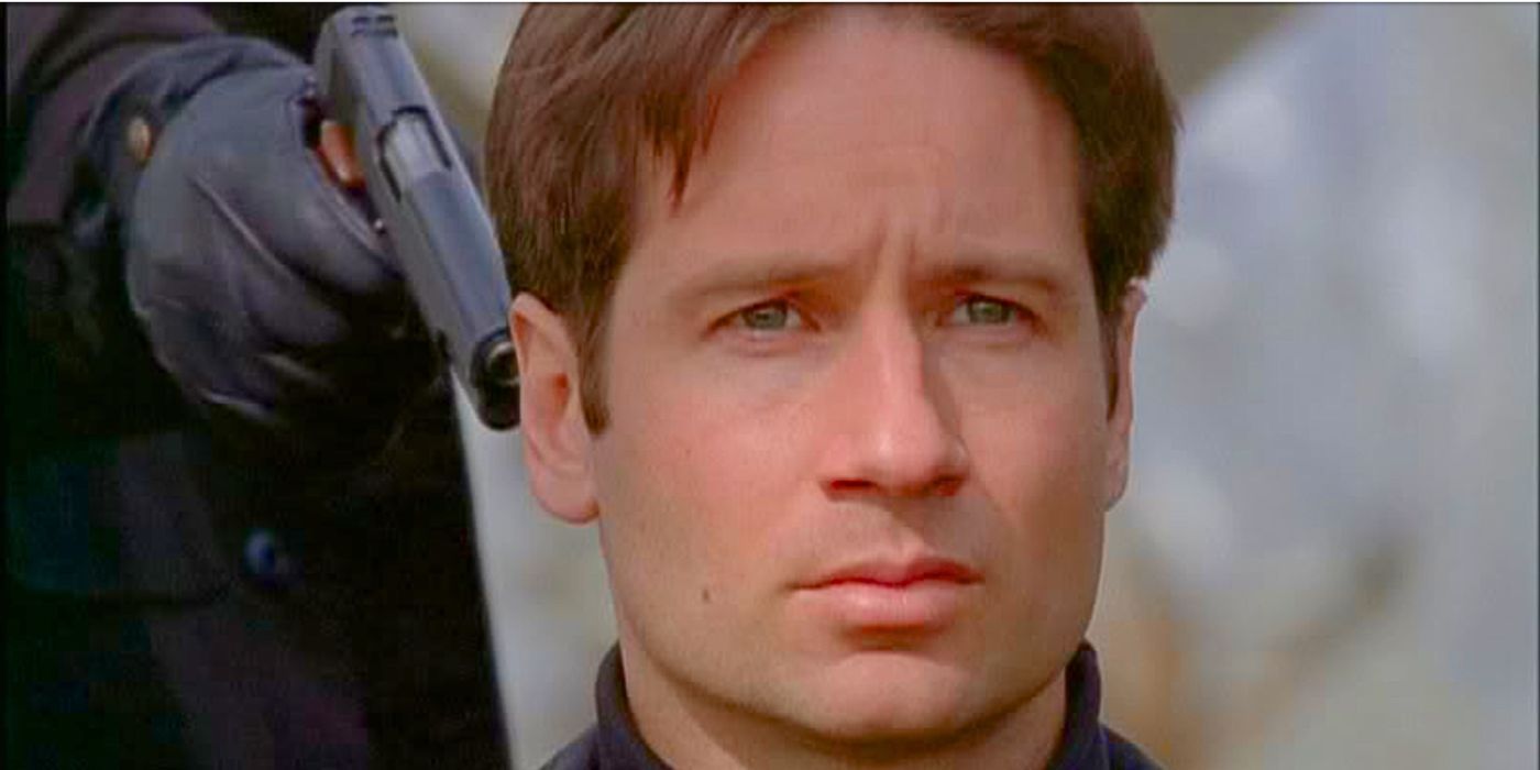 David Duchovny kneels and waits for death as an unknown male points a gun at the back of his head in the episode The Pine Bluff Variant from The X-Files