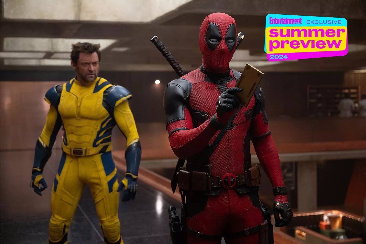 Deadpool holding a small tablet with Wolverine standing behind him in the TVA in Deadpool & Wolverine