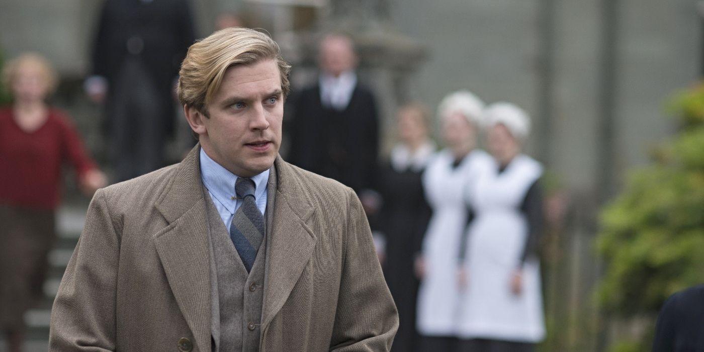 Dan Stevens como Matthew Crawley parado afuera de Downton Abbey con un traje