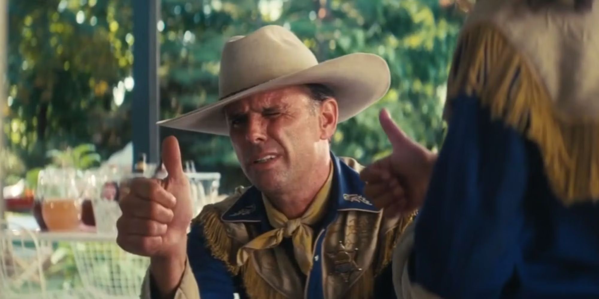 Walton Goggins giving the thumbs up while wearing a yellow and blue cowboy outfit