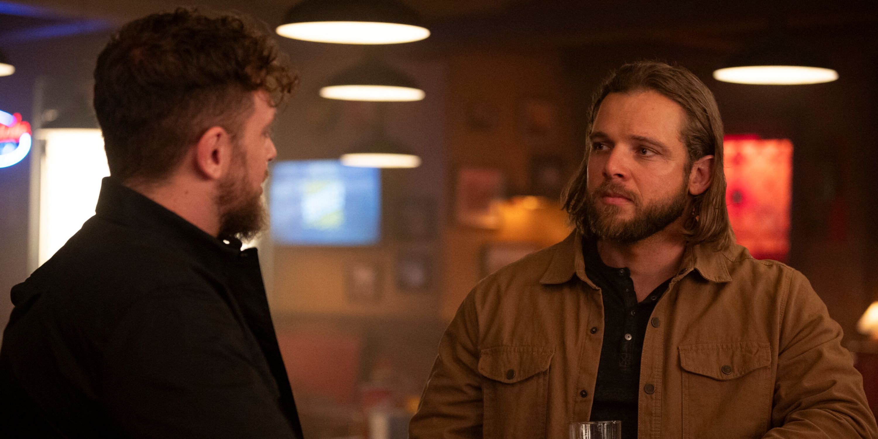 Max Thieriot as Bode Leone at a bar with an old friend back in town in Episode 10 of Season 2 of Fire Country