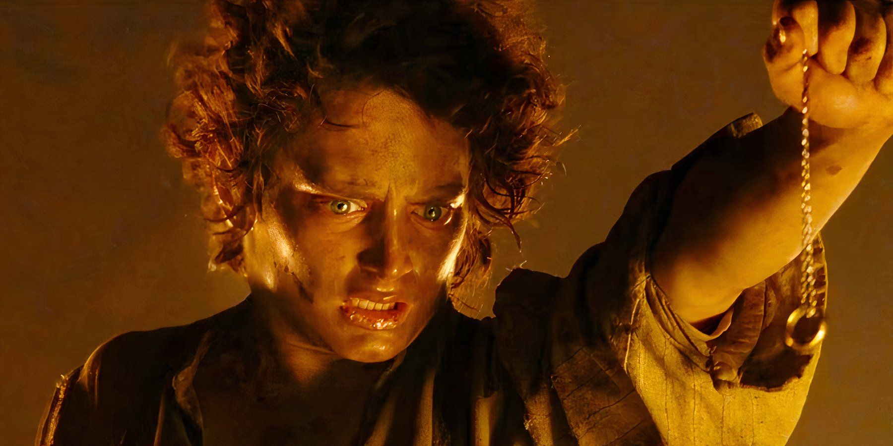 Battered and bruised, the exhausted young Hobbit Frodo Baggins, played by actor Elijah Wood, stands on the precipice of Mount Doom, preparing to cast the One Ring into the fire in The Lord of the Rings: The Return of the King.