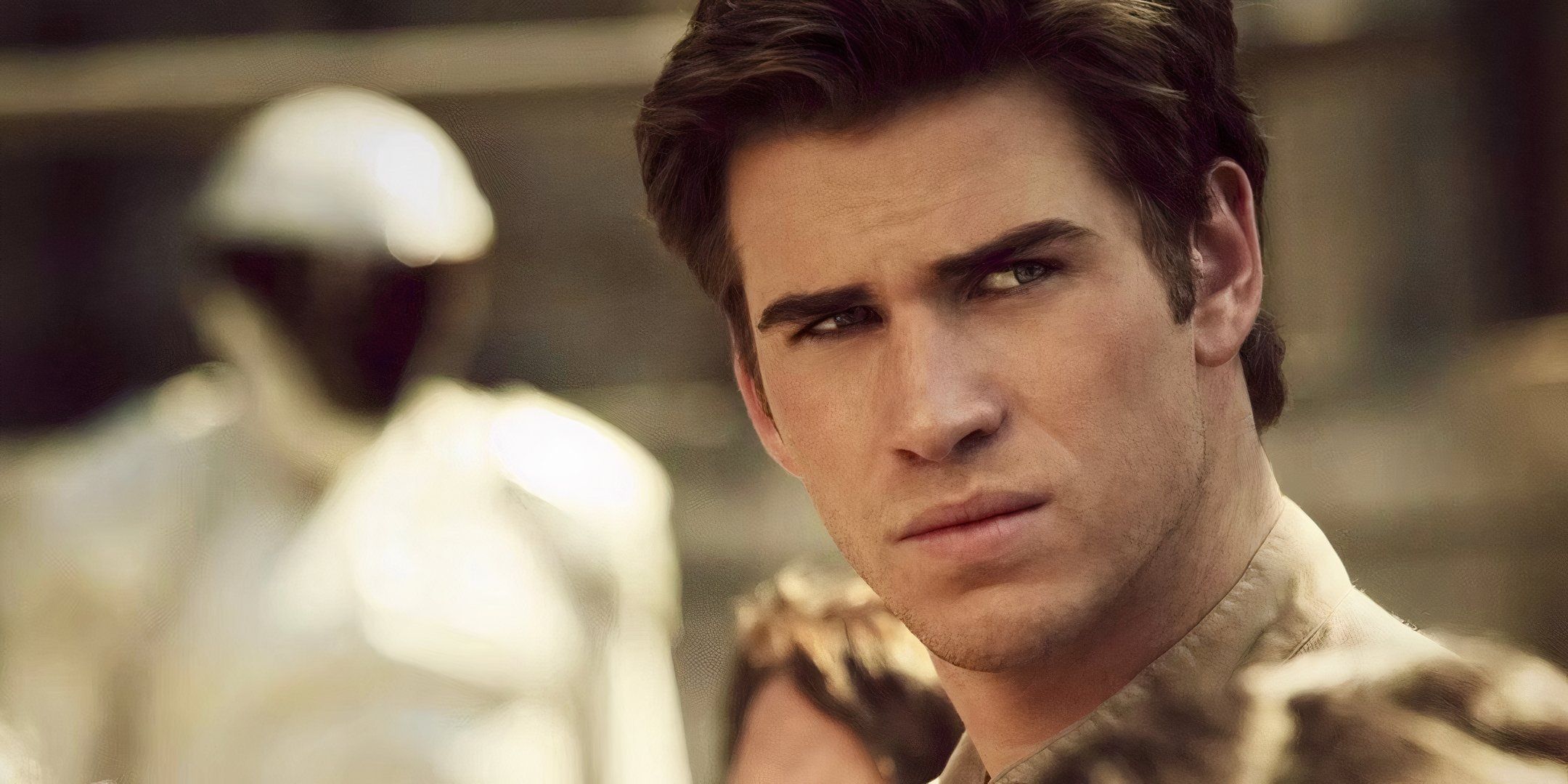 Gale Hawthorne (Liam Hemsworth) from The Hunger Games stands in District 12 at the Reaping, looking angry