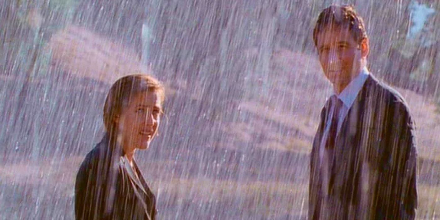 Gillian Anderson and David Duchovny are soaked as they stand fully clothed in a sudden downpour in episode The Rain King from The X-Files